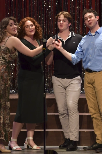 Four teen performers sing together at a microphone during a live theatre camp production at Maples Repertory Theatre in Macon, Missouri, in front of a glittering gold curtain backdrop.